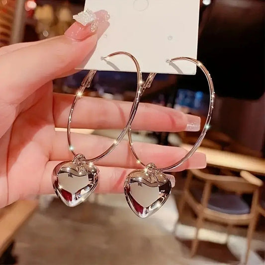 Close-up of gold and silver heart hoop earrings, showcasing the smooth, shiny metal finis