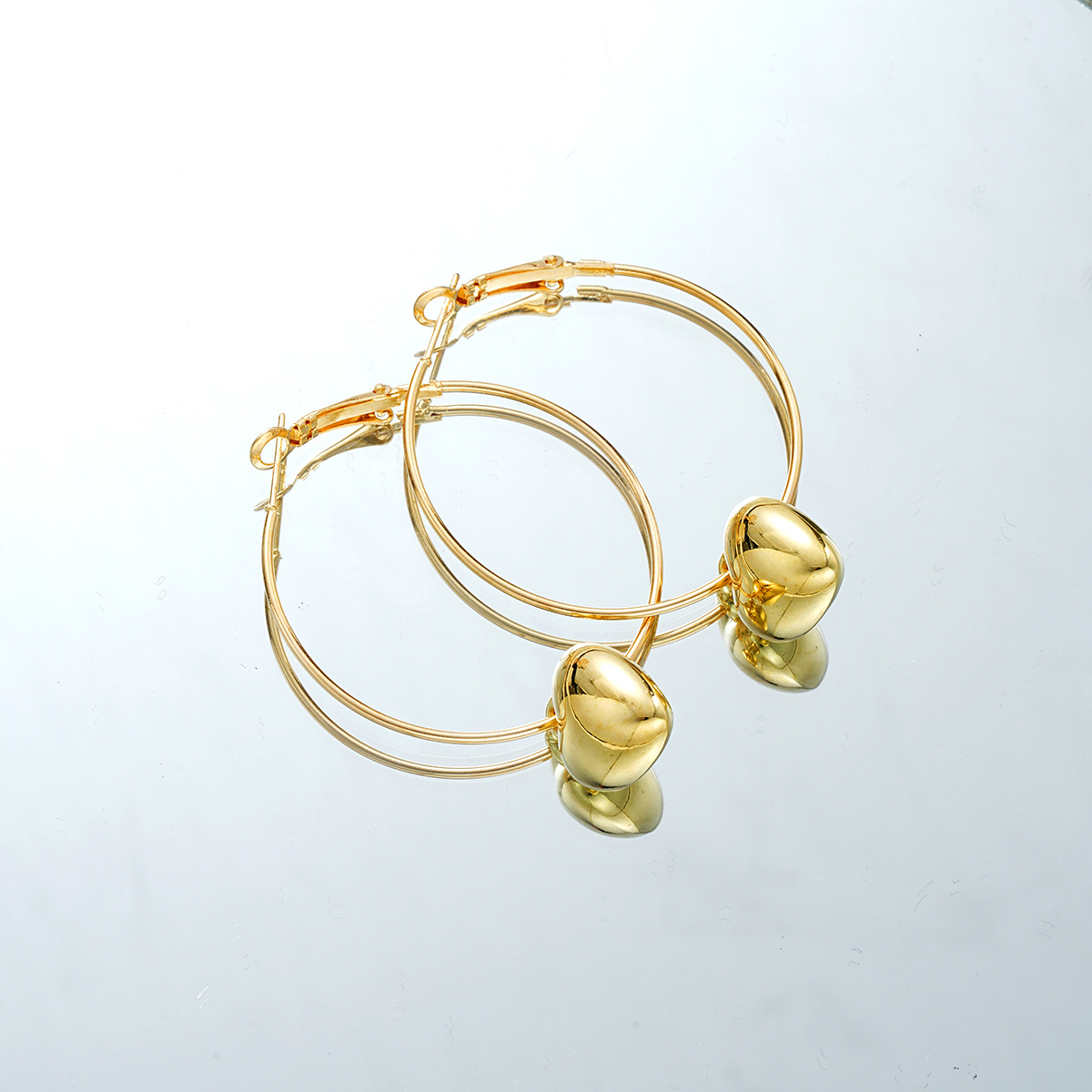 Single gold heart hoop earring, highlighting the sleek, minimalist metal hoop