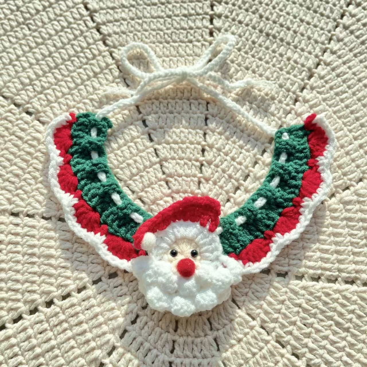 Green and red crochet pet collar with white pom-poms and a bell, laid out to highlight its festive Christmas desig
