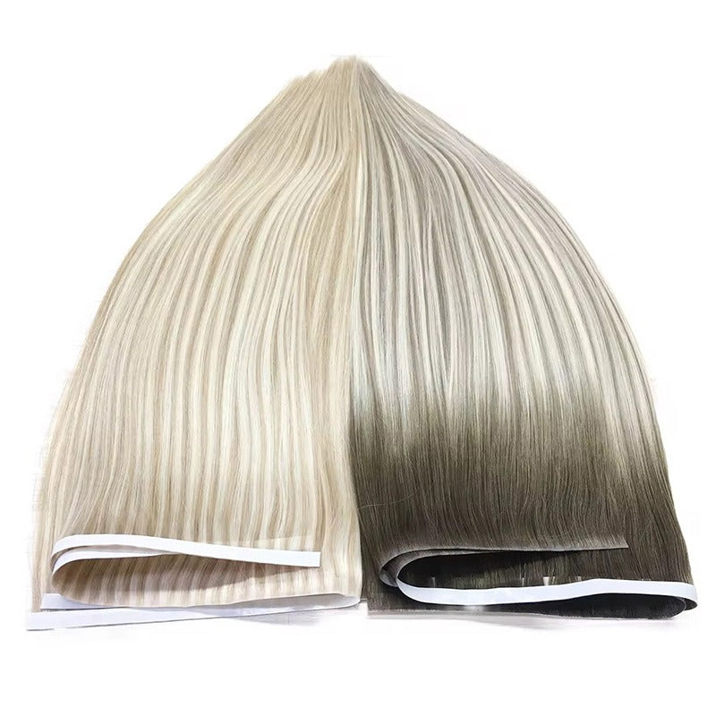 Ombre-style tape-in hair extensions with a gradient from light to dark, laid flat to show the seamless color transition.